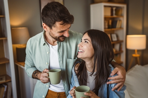 man and woman drinking out of coffee mugs